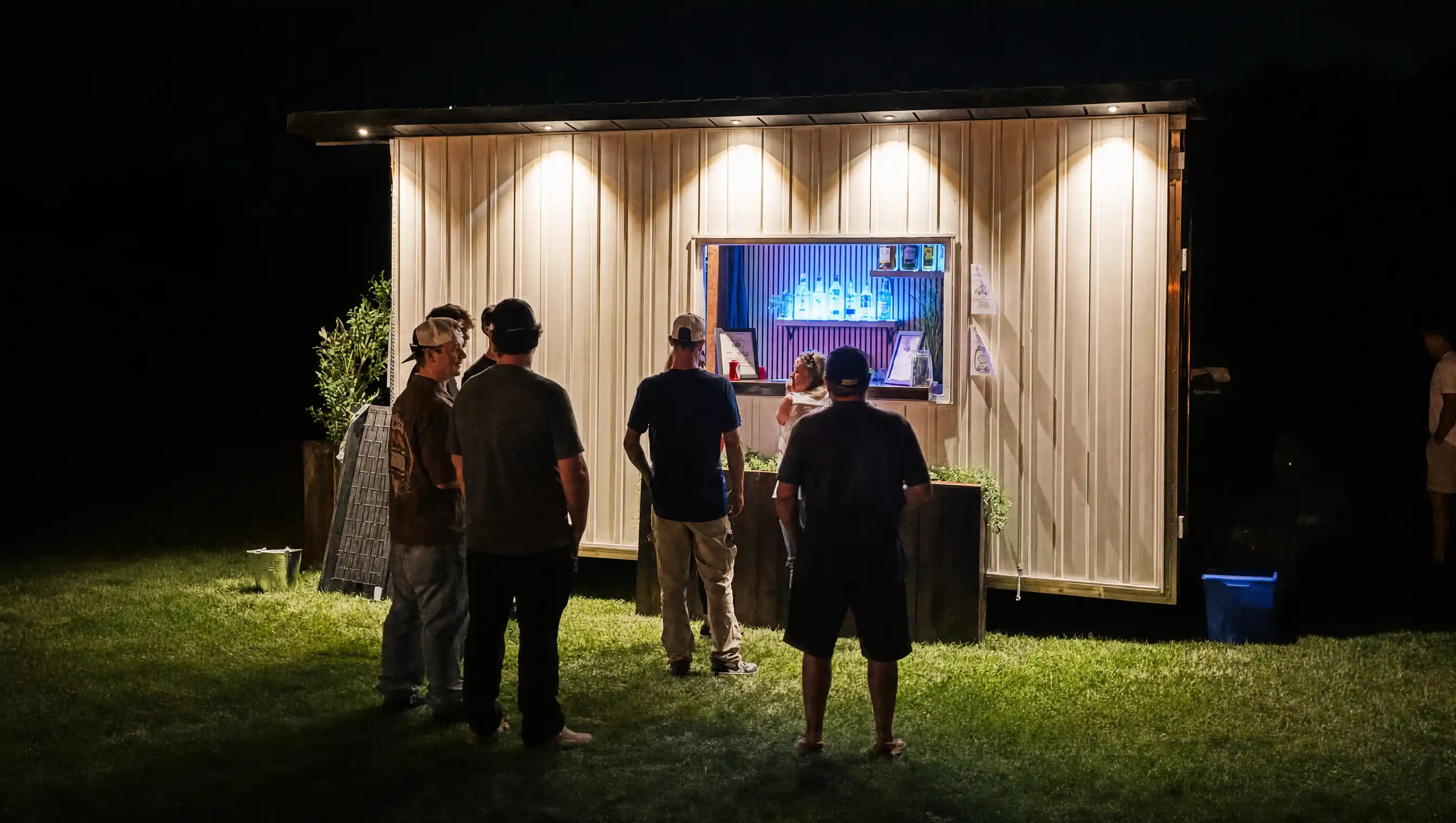 Guests gathered at The Loaded Wagon's service window at night, lit by warm string lights.