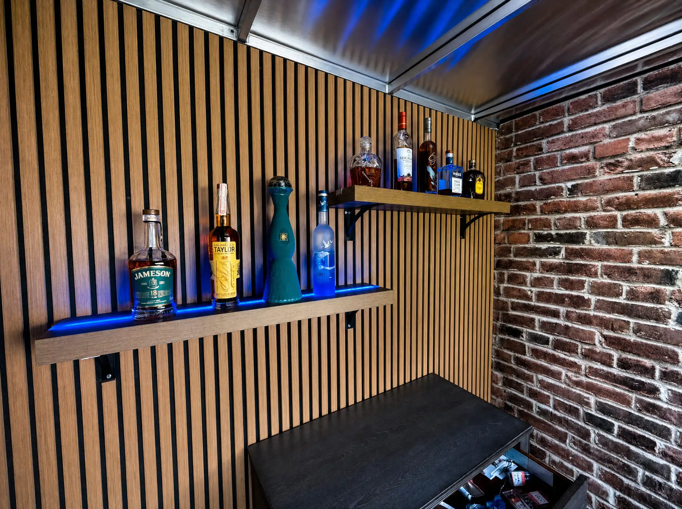 Shelves of premium liquor bottles lit with cool blue accent lighting.